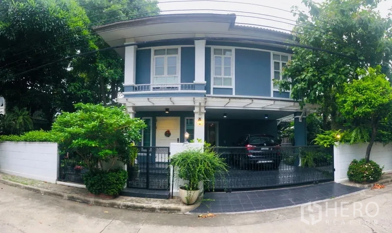 独立式住宅 出租在Bang Kapi, Bangkok - 正面全景，铁艺大门、铺砖车道与有顶停车区。