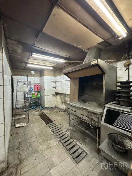 Retail Space for rent in Yan Nawa, Bangkok - Commercial kitchen with exhaust hood, grill and tiled walls needing refurbishment.