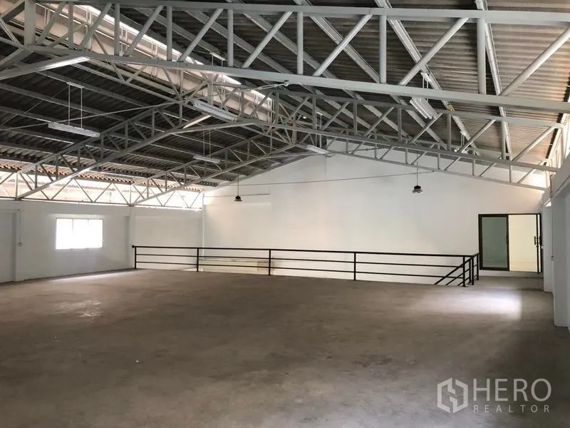 Factory for rent in Pak Kret, Nonthaburi - Large truss-roof factory hall from another angle with safety railing and side windows.