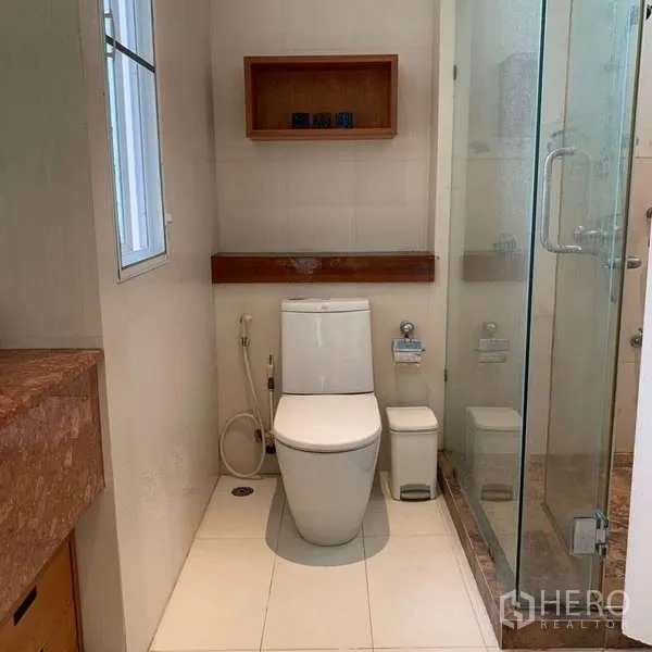 Detached House for rent in Lat Krabang, Bangkok - Compact bathroom area with window, toilet and a glass-enclosed shower.
