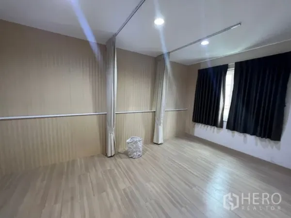 Home Office for rent - Multi-purpose room with wood panel walls, curtain tracks for partitions, and window with dark drapes.