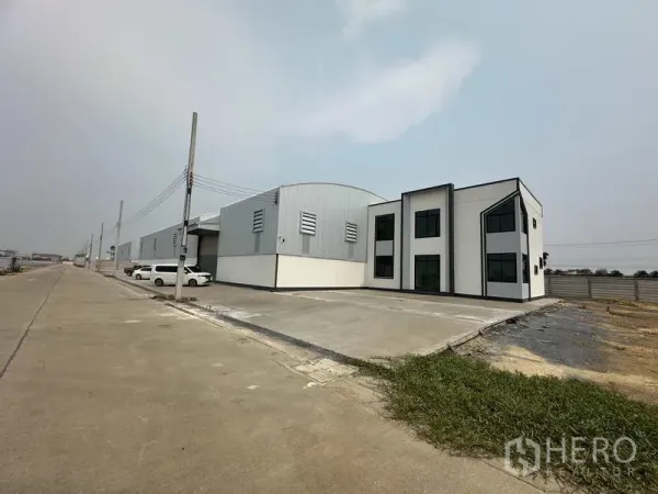 Factory for rent or sale in Sai Noi, Nonthaburi - Angled view of factory and office showing expansive truck access apron and perimeter fence.