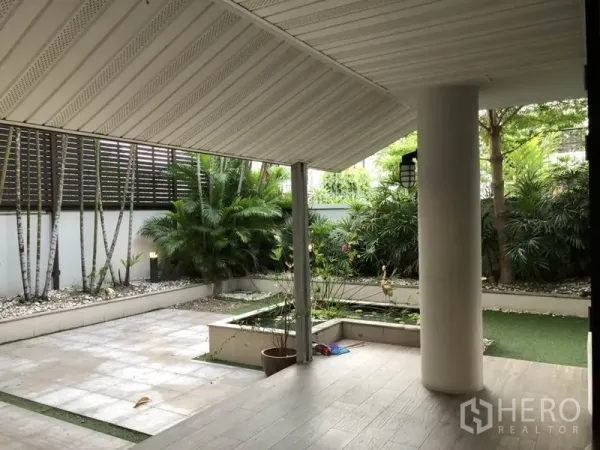 Detached House for rent in Bang Rak, Bangkok - Shaded patio with slanted roof beside landscaped garden, planters, and water feature.