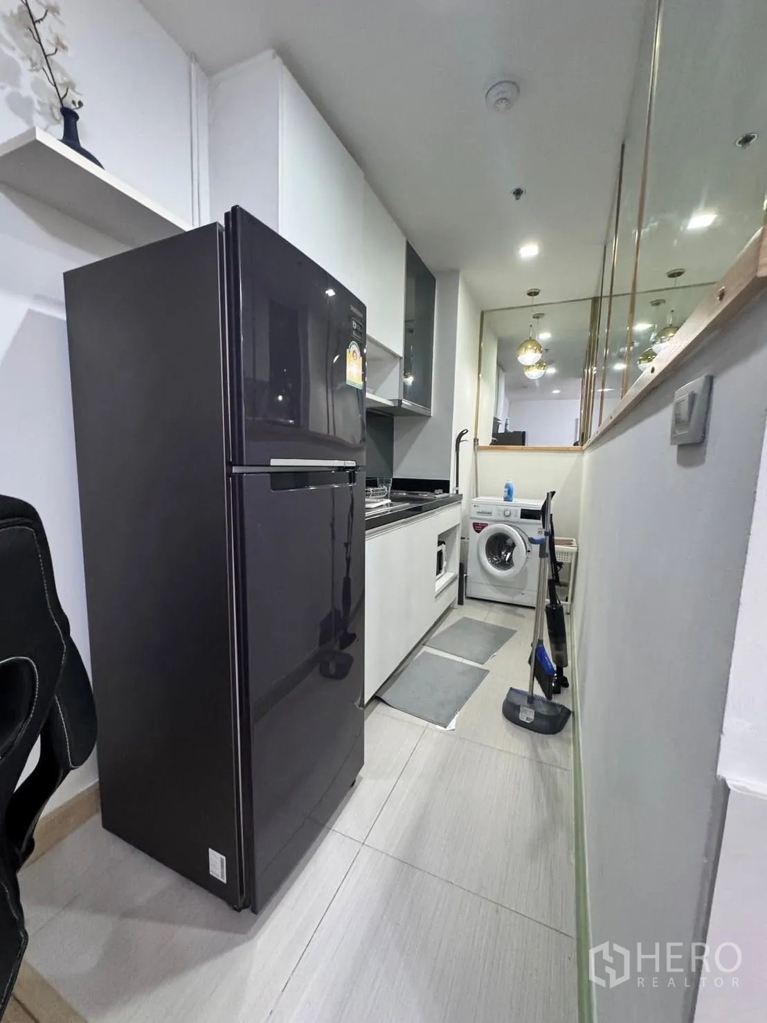 คอนโด for rent in Watthana, Bangkok - ครัวแคบแบบแกลลีย์พร้อมตู้เย็นสีดำ ตู้เก็บของ อ่างล้าง และเครื่องซักผ้า