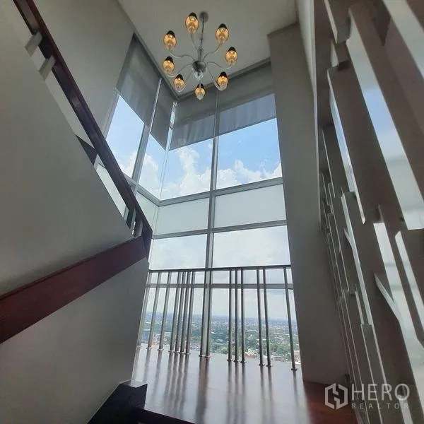公寓 出租在Bang Kapi, Bangkok - 楼梯平台，挑高转角落地窗与现代吊灯。