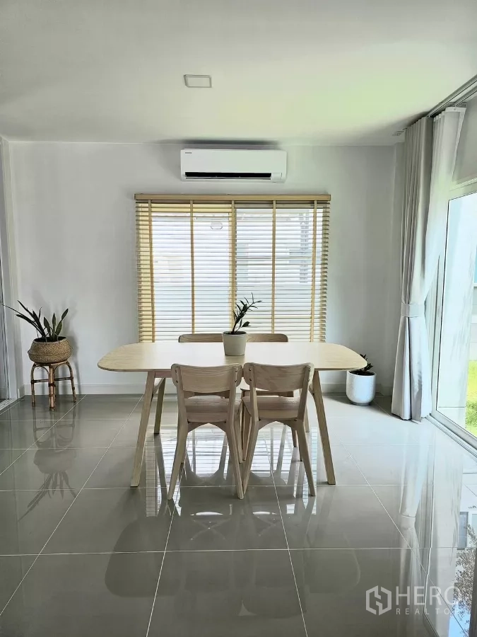 Detached House for rent in Bang Phli, Samut Prakan - Light-filled dining area with wooden table, four chairs, blinds and sliding doors.