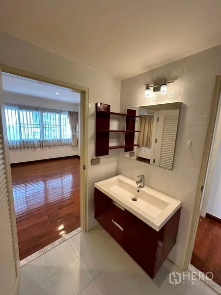 Condominium for rent in Bangkok - Vanity area with shelves and mirror positioned between bedroom and bathroom under modern lighting.