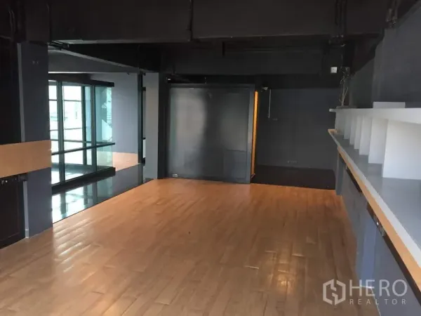 Retail Space for rent in Khlong Toei, Bangkok - Open-plan retail space with wood flooring, dark industrial ceiling, built-in display shelf and glass wall.