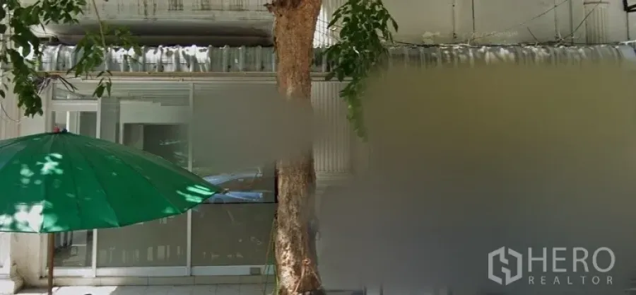 Retail Space for rent in Bang Rak, Bangkok - Glass-fronted shop entrance with sliding doors, shaded sidewalk, a roadside tree and a green umbrella along a retail row in Bang Rak.