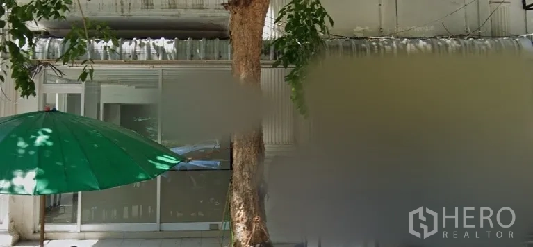 Retail Space for rent in Bang Rak, Bangkok - Glass-fronted shop entrance with sliding doors, shaded sidewalk, a roadside tree and a green umbrella along a retail row in Bang Rak.