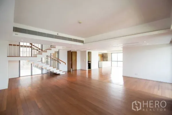 Condominium for rent in Yan Nawa, Bangkok - Expansive duplex living and dining space with floating staircase and open kitchen.
