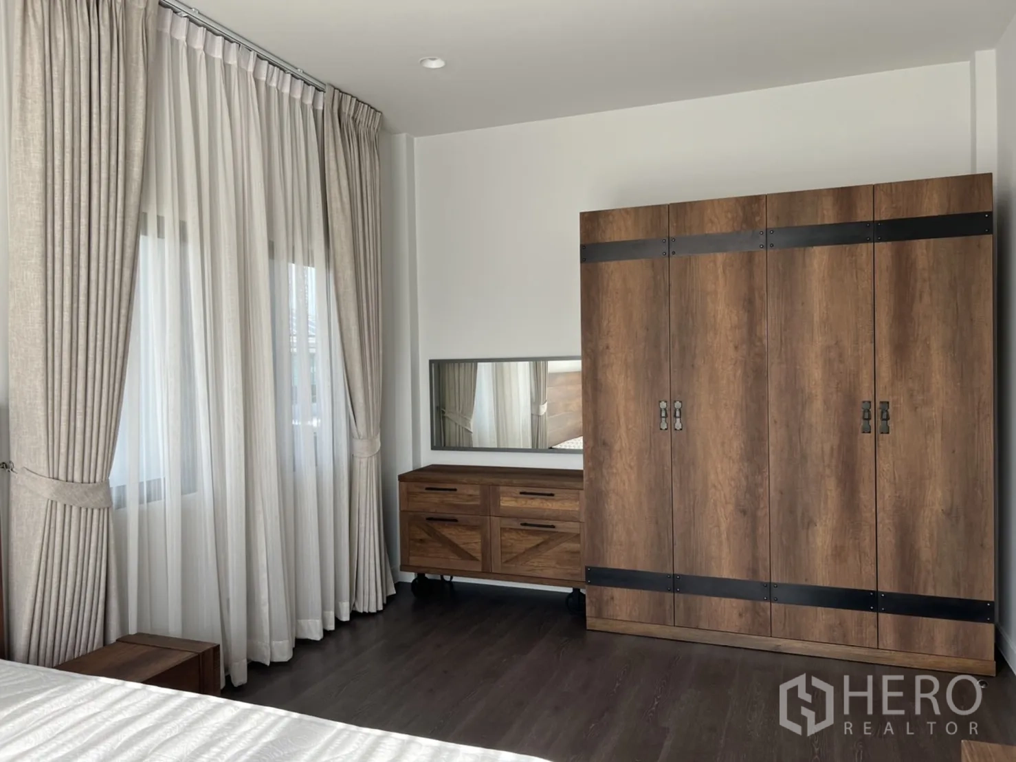 Detached House for rent in Bang Kapi, Bangkok - Guest bedroom with wooden wardrobe, dresser, and large curtained windows.