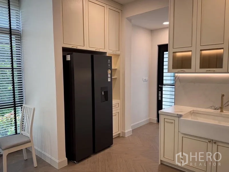 Detached House for rent or sale - Light-toned kitchen with a black side-by-side fridge, farmhouse sink, and ample cabinetry.