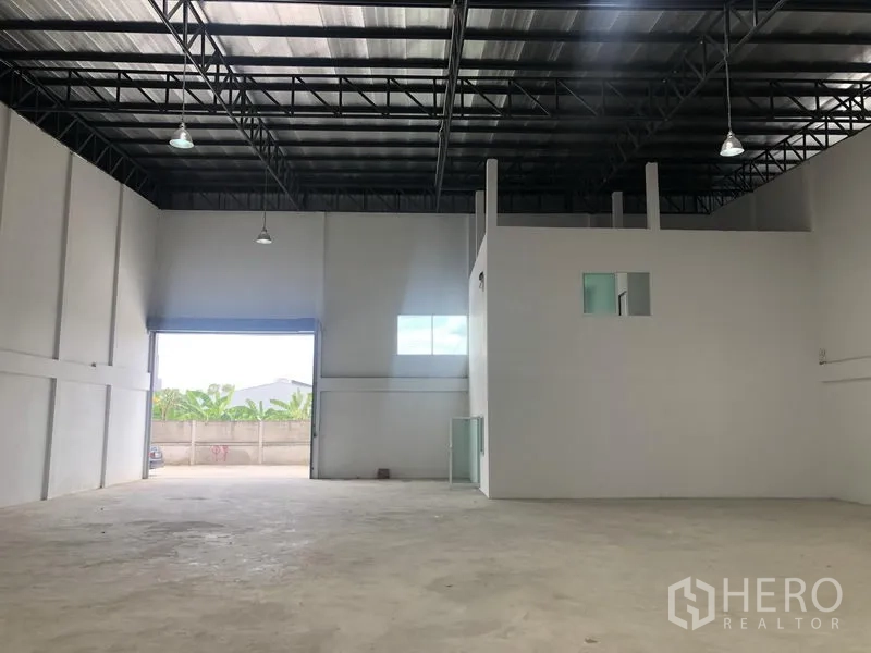 Factory for rent in Sai Noi, Nonthaburi - Warehouse interior with wide roller door opening, mezzanine office block and concrete floor.