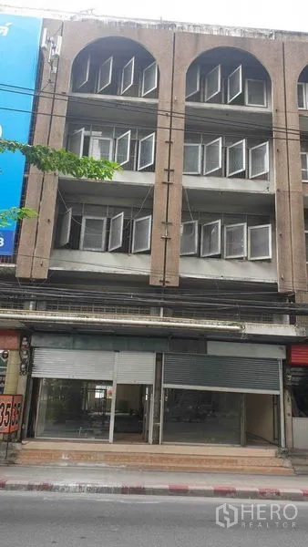 Shophouse for rent in Phra Khanong, Bangkok - Four-storey shophouse facade with arched windows and a roller shutter storefront.