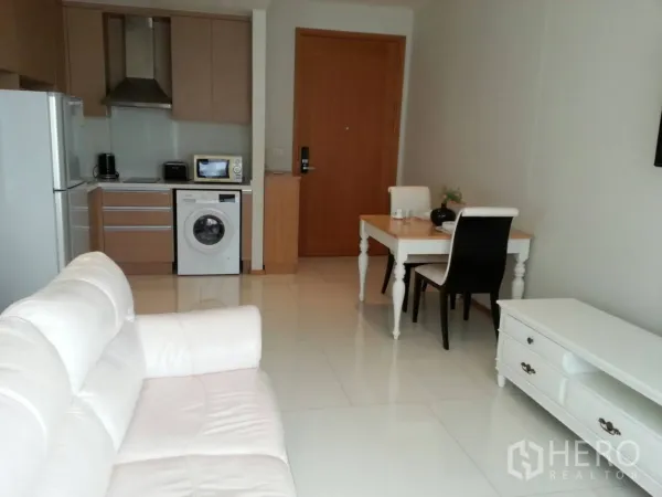 公寓 出租在Khlong Toei, Bangkok - 开放式客厅，白色沙发，带洗衣机的简洁厨房和餐桌，素坤逸公寓内景