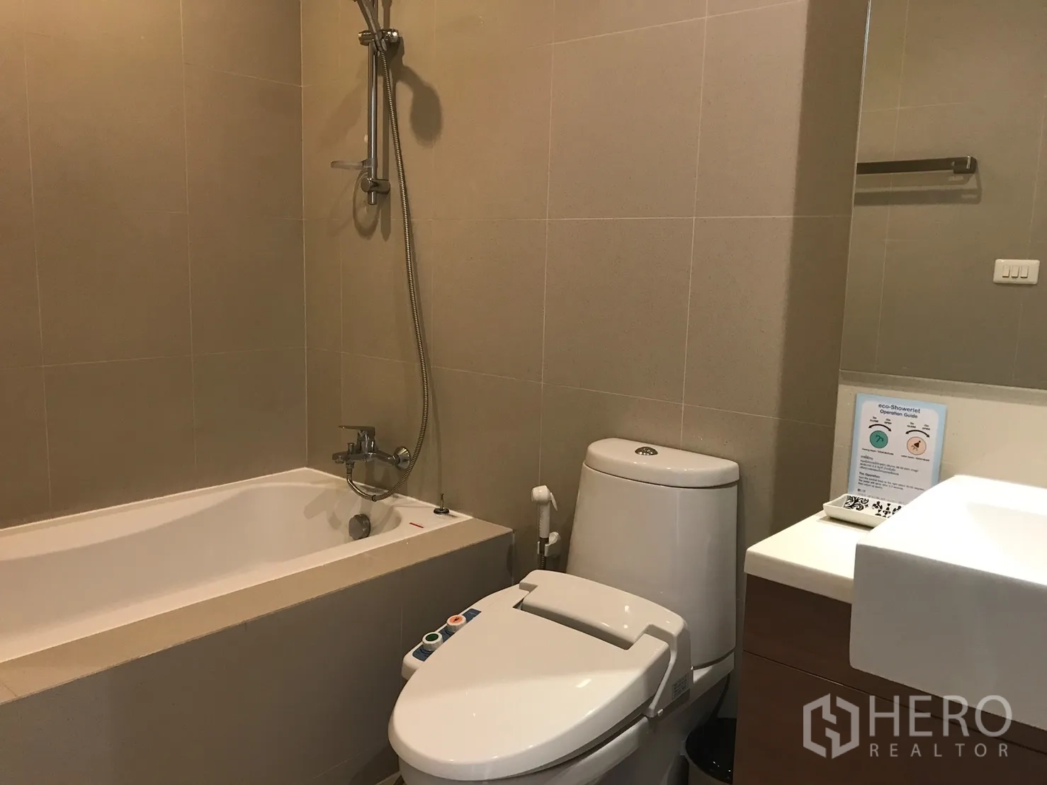 Condominium for rent in Bangkok - Modern bathroom featuring a bathtub with shower, vanity sink, and bidet-style toilet.