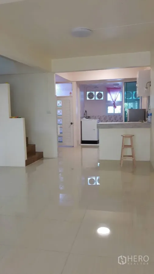 联排别墅 出租在Khlong Toei, Bangkok - 开放式客厅，亮面地砖、楼梯与可见的小厨房和吧台。