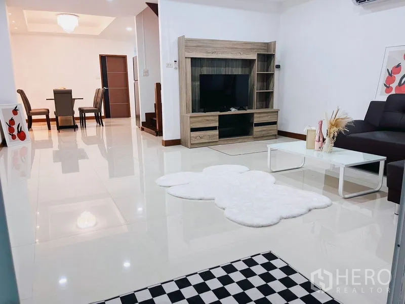 Townhouse for rent in Huai Khwang, Bangkok - Open-plan living with TV console, L-shaped sofa and glossy tile floors.