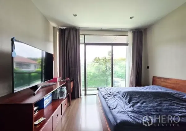 Detached House for sale in Bang Kapi, Bangkok - Master bedroom with sliding glass door to balcony and wooden TV console.