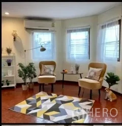 Detached House for rent in Phra Khanong, Bangkok - Cozy corner sitting area with two armchairs, geometric rug, shelves and windows.
