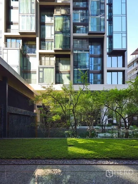 公寓 出租或出售在Pathum Wan, Bangkok - 现代公寓外立面，大片玻璃窗俯瞰草坪与绿意花园