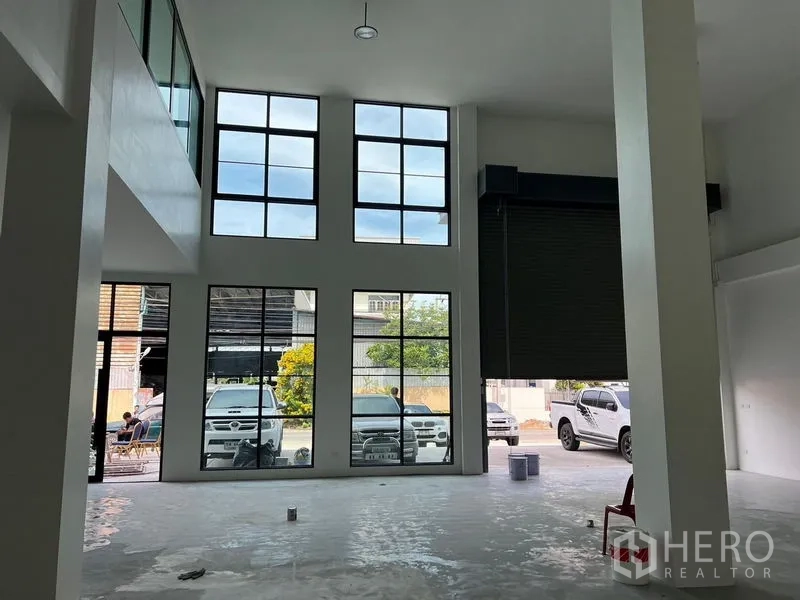 Warehouse for rent in Bang Sao Thong, Samut Prakan - Double-height loading area with floor-to-ceiling windows and a wide roller door for truck access.