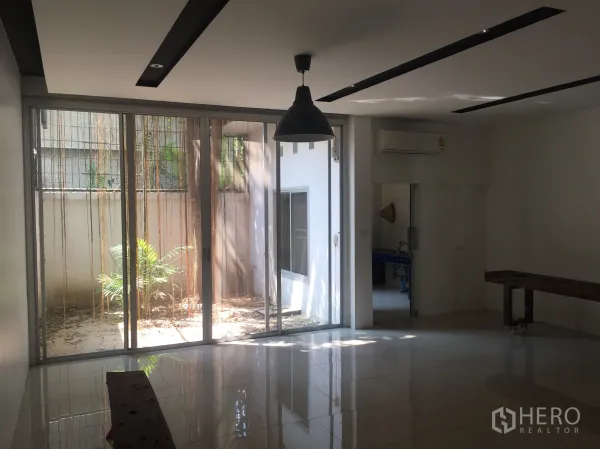 Townhouse for rent in Bang Rak, Bangkok - Open-plan area with sliding glass doors to a private courtyard, pendant light and tiled floor near Chong Nonsi.