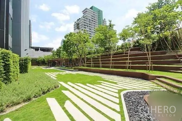 คอนโด ขายในBang Rak, Bangkok - สวนภายนอกจัดภูมิทัศน์ ลานหญ้าไล่ระดับ ต้นไม้ และอาคารสูงสมัยใหม่ด้านหลัง