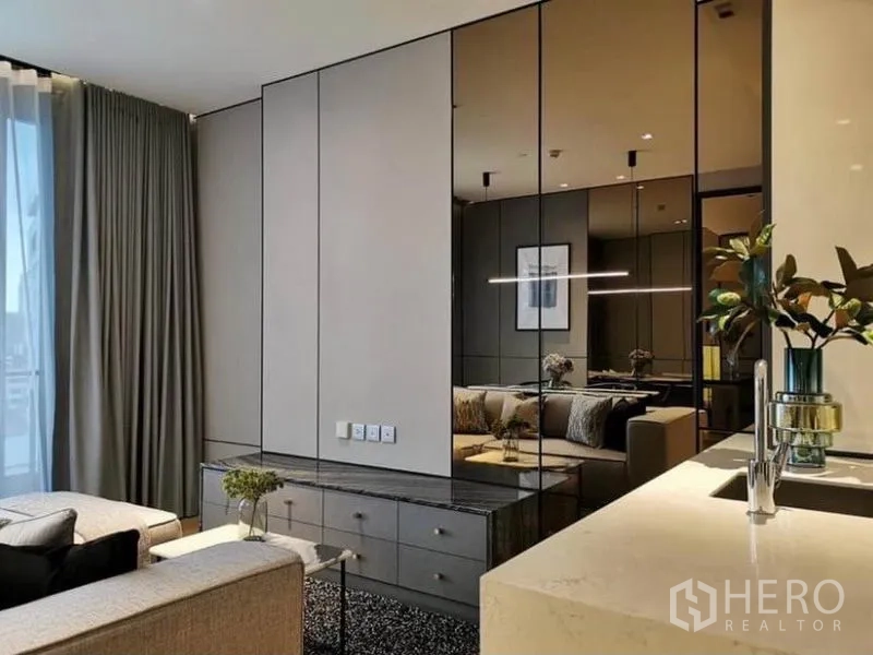Condominium for rent in Khlong Toei, Bangkok - TV console with mirrored cabinets next to kitchen sink counter