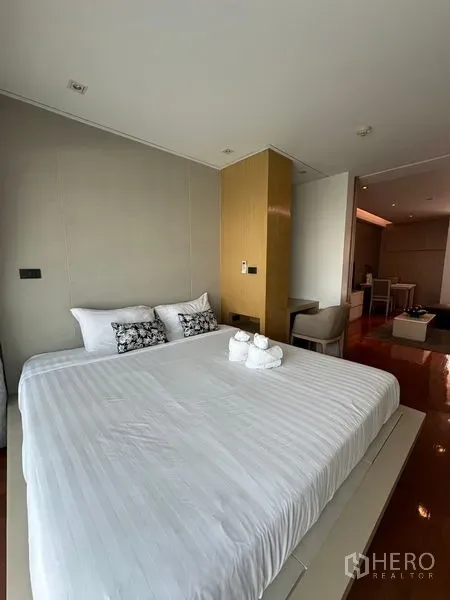 Apartment for rent in Khlong Toei, Bangkok - Bright bedroom with king-size bed, wood floors, and soft headboard.