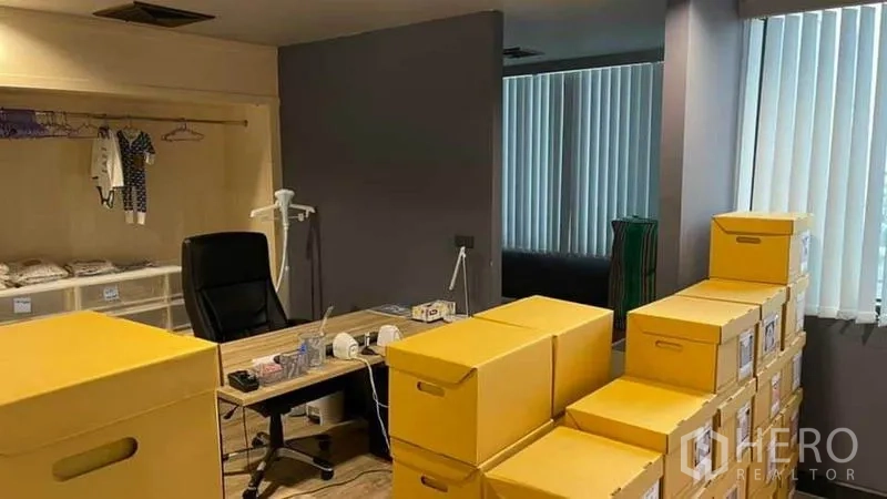 Office Space for rent in Khlong Toei, Bangkok - Storage and packing room with stacks of yellow boxes beside a manager’s desk.