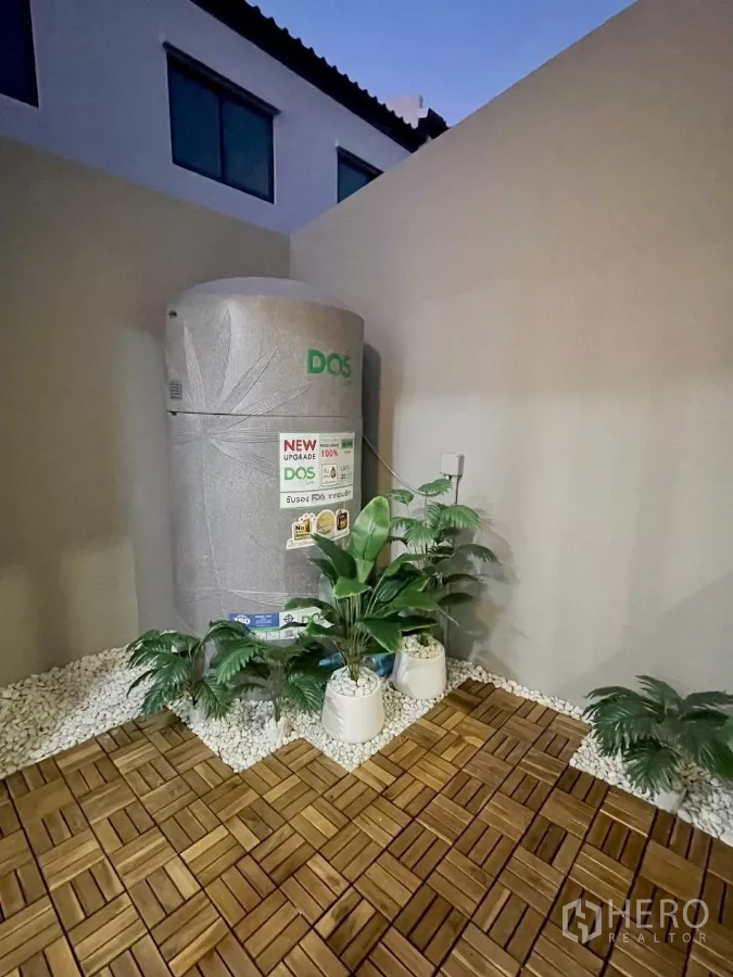 Townhouse for rent in Samut Prakan - Rear patio laundry area with wood deck tiles, white stones and water tank.