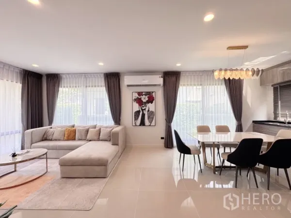 Detached House for rent or sale in Bang Kapi, Bangkok - Bright open-plan living and dining area with L-shaped sofa and six-seat dining table.