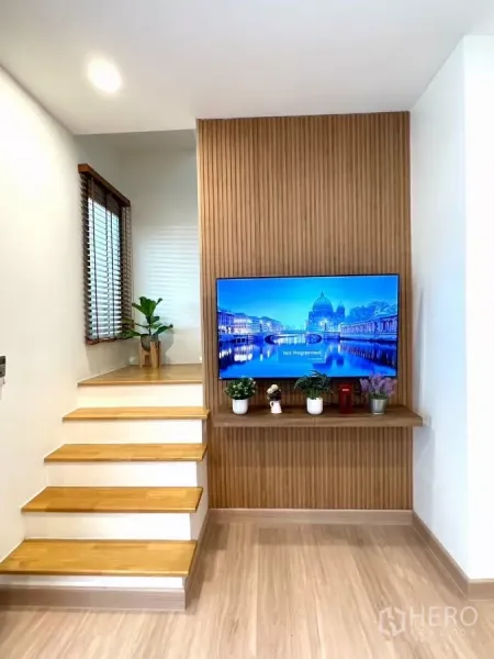 联排别墅 出租在Bang Phli, Samut Prakan - 木质楼梯与竖向木饰面电视墙，点缀绿植。