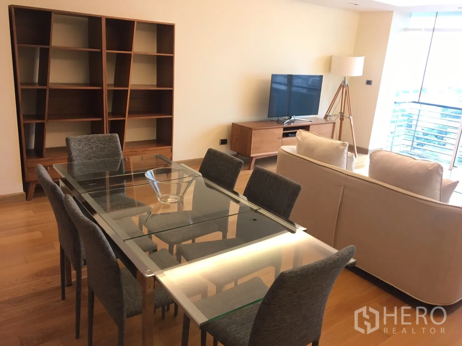 Condominium for rent in Phaya Thai, Bangkok - Dining area and lounge with TV console, floor lamp, balcony window and built-in shelving.