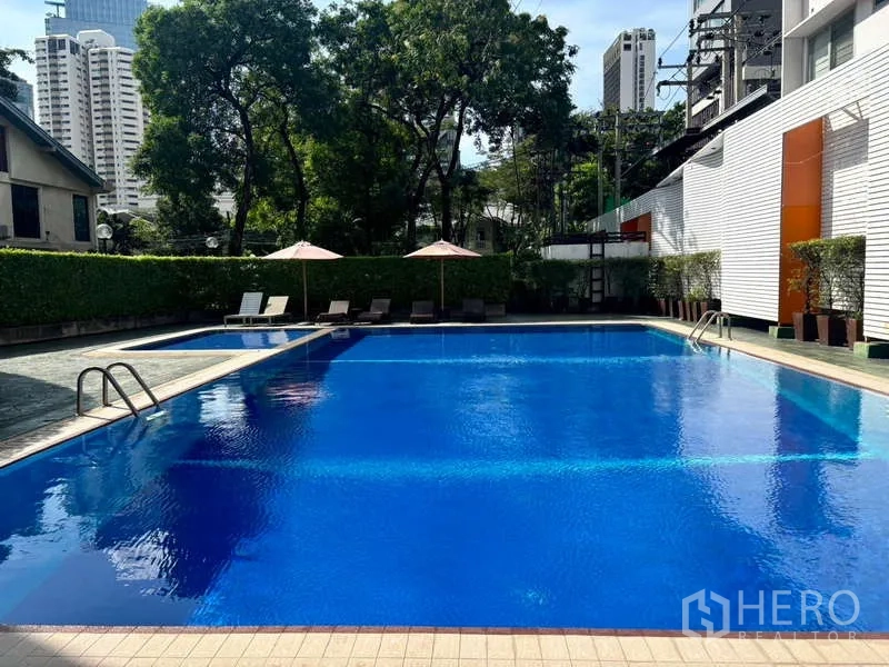 Condominium for rent in Watthana, Bangkok - Outdoor condominium swimming pool with sun loungers and greenery.