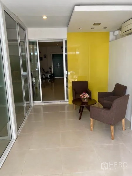 带办公室的家 出租在Wang Thonglang, Bangkok - 等候区，两张扶手椅、圆桌与黄色重点墙面。