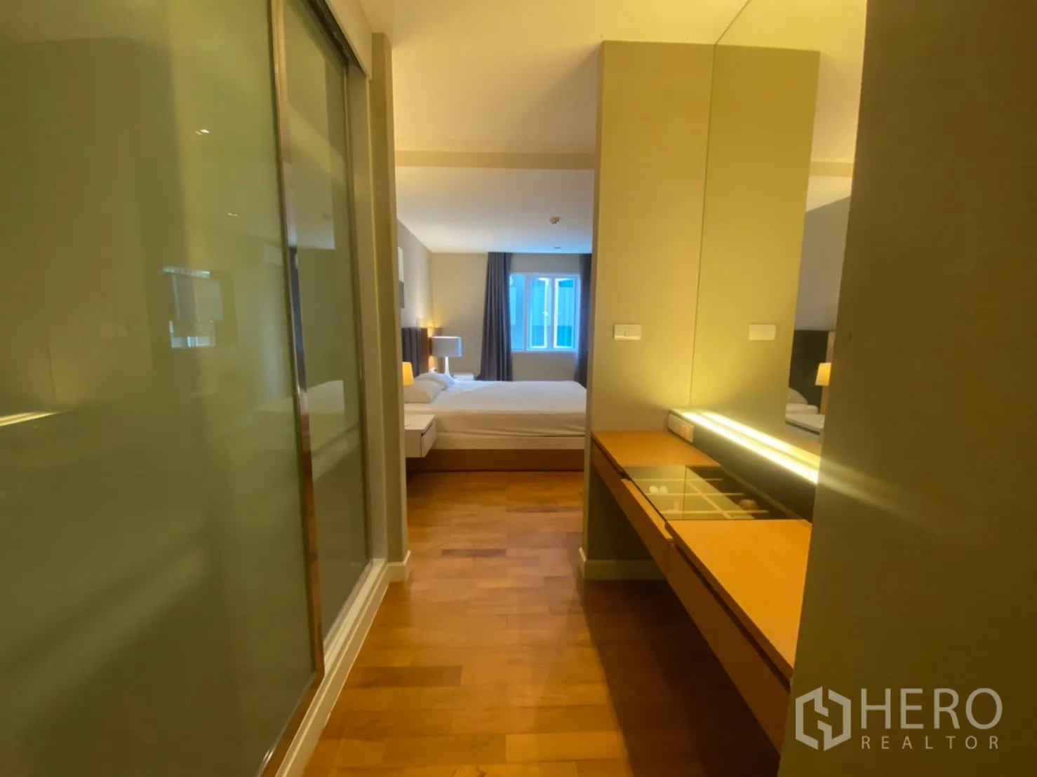 公寓 出租在Watthana, Bangkok - 过道设梳妆台与镜面收纳，通往木地板卧室。