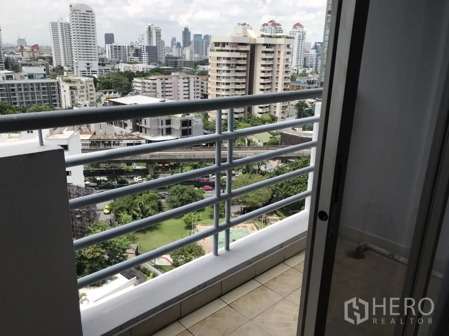 Condominium for rent in Khlong Toei, Bangkok - Small balcony with railings overlooking the city and a pool below.