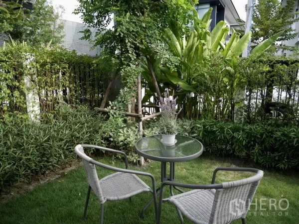 Detached House for rent in Bang Kapi, Bangkok - Lush private garden with round glass table and two chairs beneath trees and hedges.