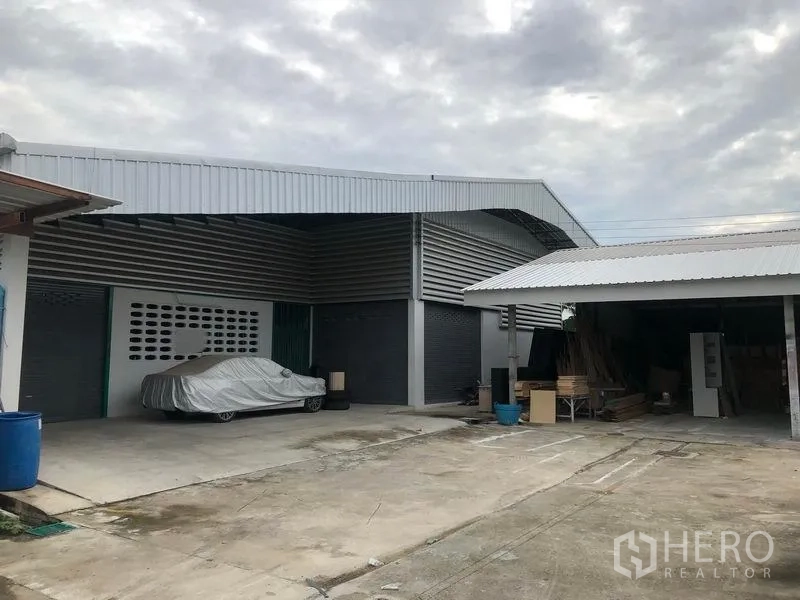 货栈 出租在Mueang Pathum Thani, Pathum Thani - 金属板外墙仓库，设有卷闸门、带顶装卸区与宽阔混凝土院坝，便于卡车通行与停车