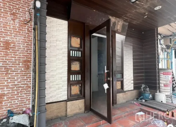 Retail Space for rent in Khlong Toei, Bangkok - Main entrance with a glass door, wood trim and tiled step beside an exposed brick wall.