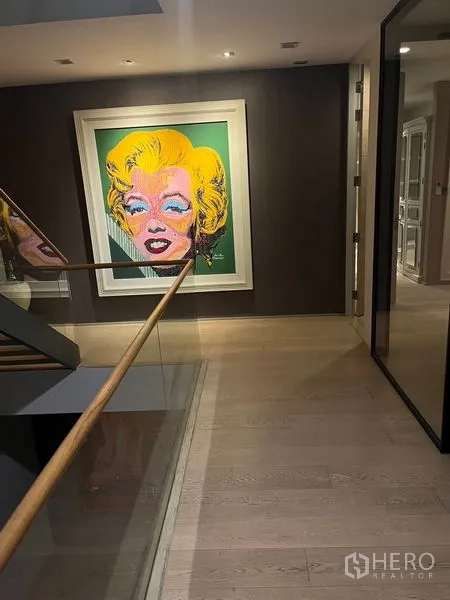 Detached House for rent in Wang Thonglang, Bangkok - Stair landing with glass balustrade and a colorful pop art portrait on a feature wall.