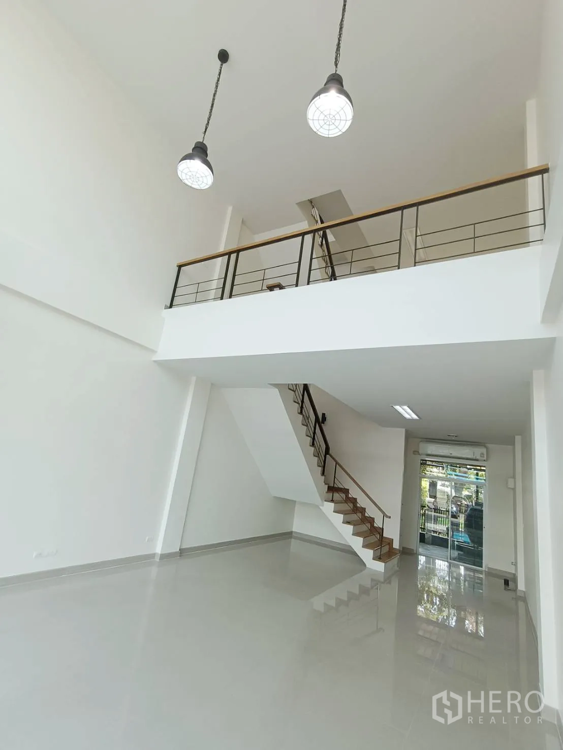 带办公室的家 for rent or sale in Prawet, Bangkok - 首层挑高空间带夹层，吊灯、楼梯与玻璃大门。