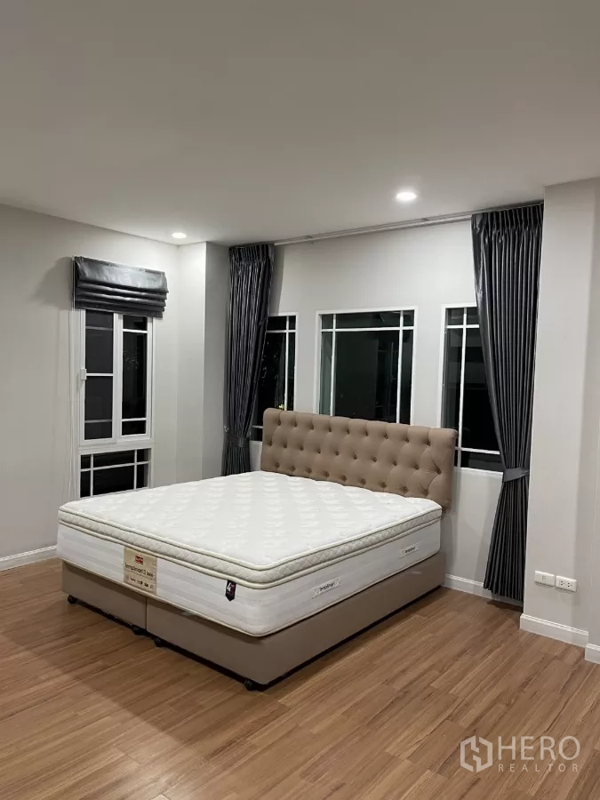 Detached House for rent in Bang Kapi, Bangkok - Spacious master bedroom with large windows and upholstered bed base.