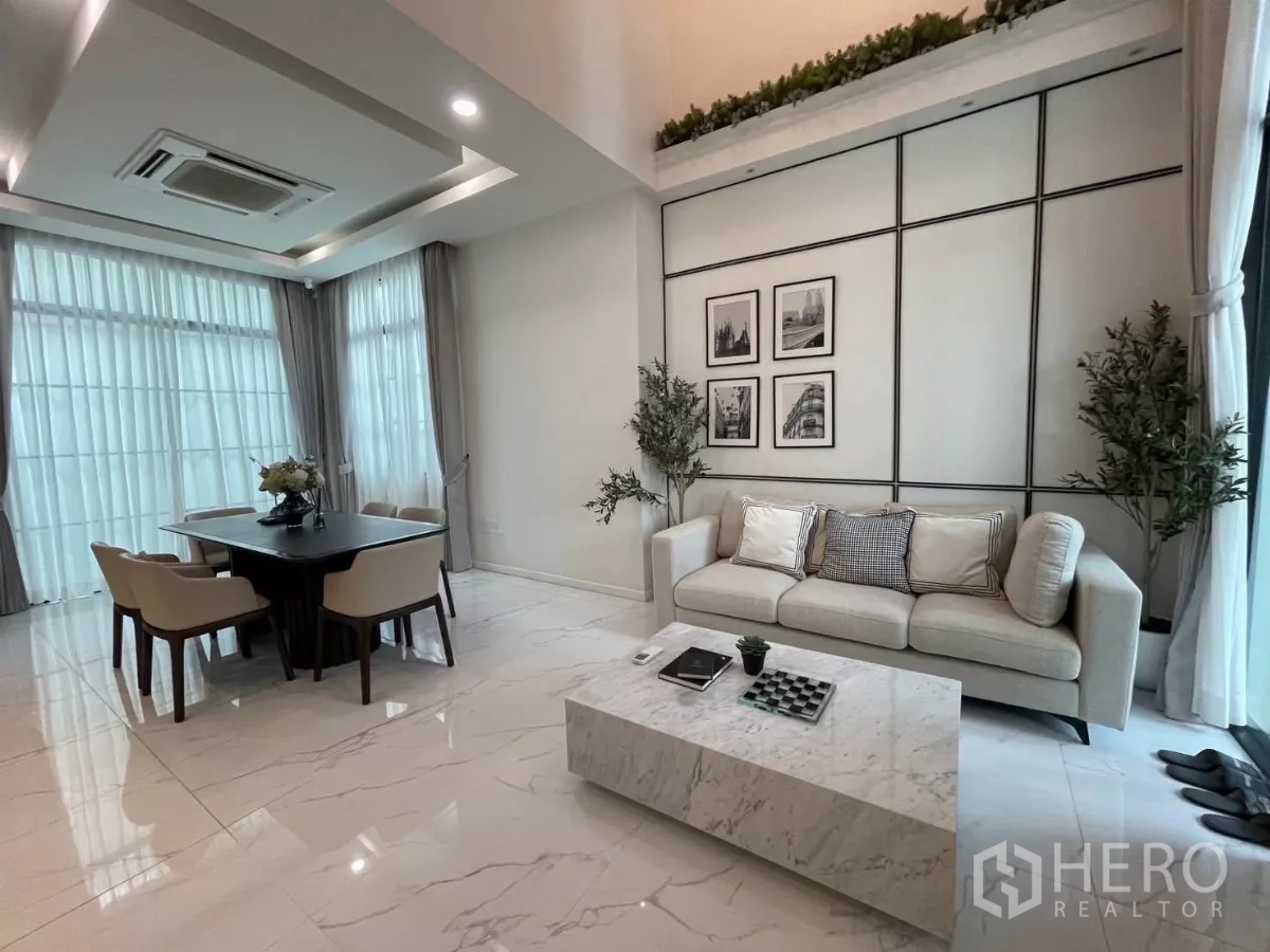 独立式住宅 出租在Lat Phrao, Bangkok - 采光充足的客餐厅，仿大理石地面，沙发与餐桌临落地窗