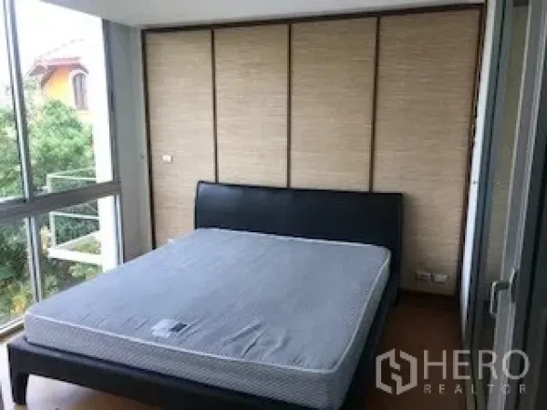 Townhouse for rent or sale in Yan Nawa, Bangkok - Bedroom with large windows, double bed and leafy neighborhood views.