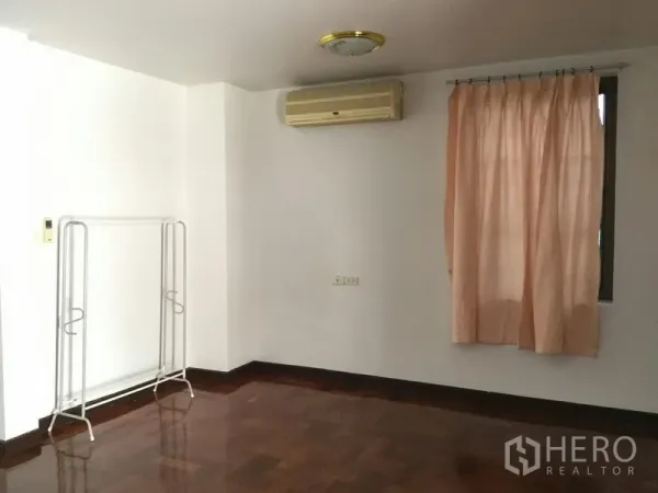独立式住宅 出租或出售在Huai Khwang, Bangkok - 简洁房间，窗帘、壁挂空调与衣架，木地板。