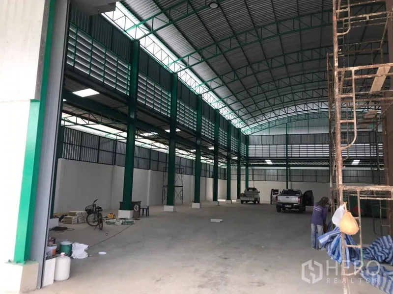 Factory for rent or sale in Mueang Samut Sakhon, Samut Sakhon - Long warehouse aisle with ventilation panels and green steel columns.